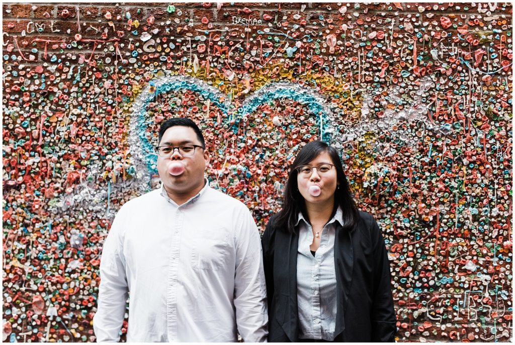 A couple blowing bubbles at the gum wall for their Seattle engagement photos