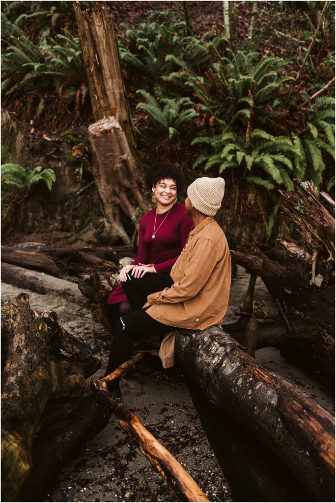 An LGBTQ+ couple smile at each other in the woods during their Point Defiance engagement session