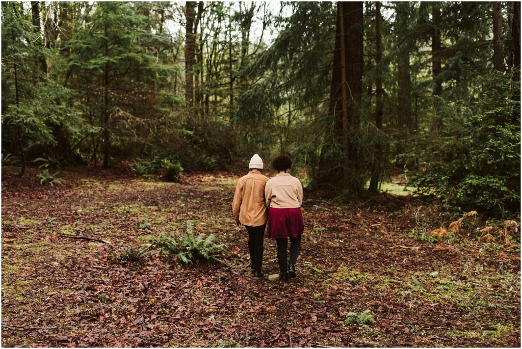 LGBTQ couple walking arm and arm through the forest at Point Defiance for their Seattle engagement photos