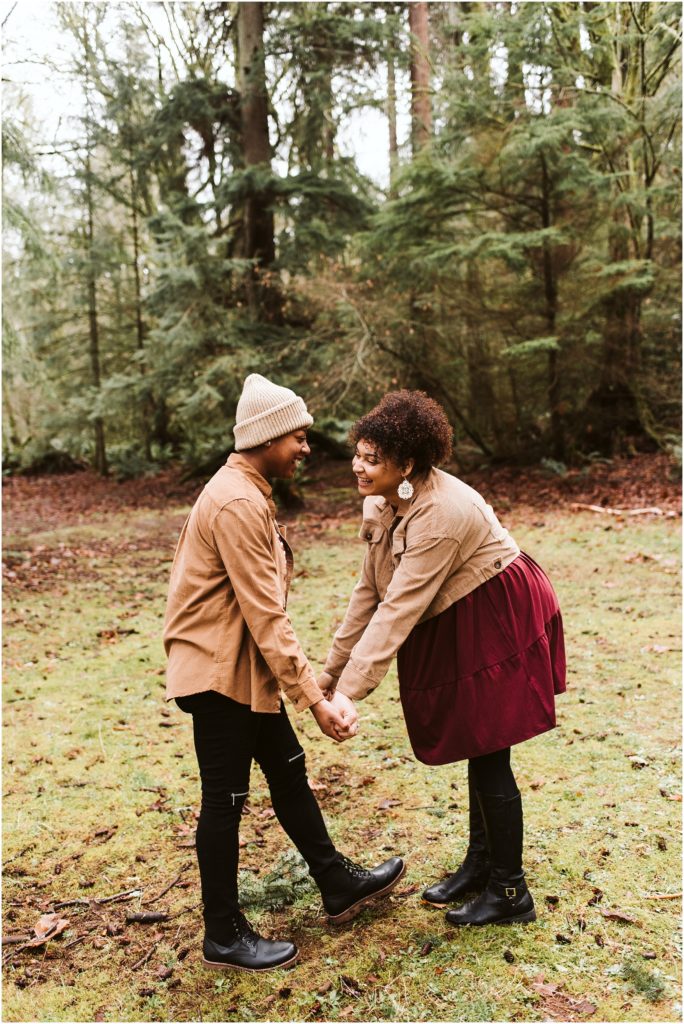 An LGBTQ+ couple holding hands and giggling during their Point Defiance engagement session