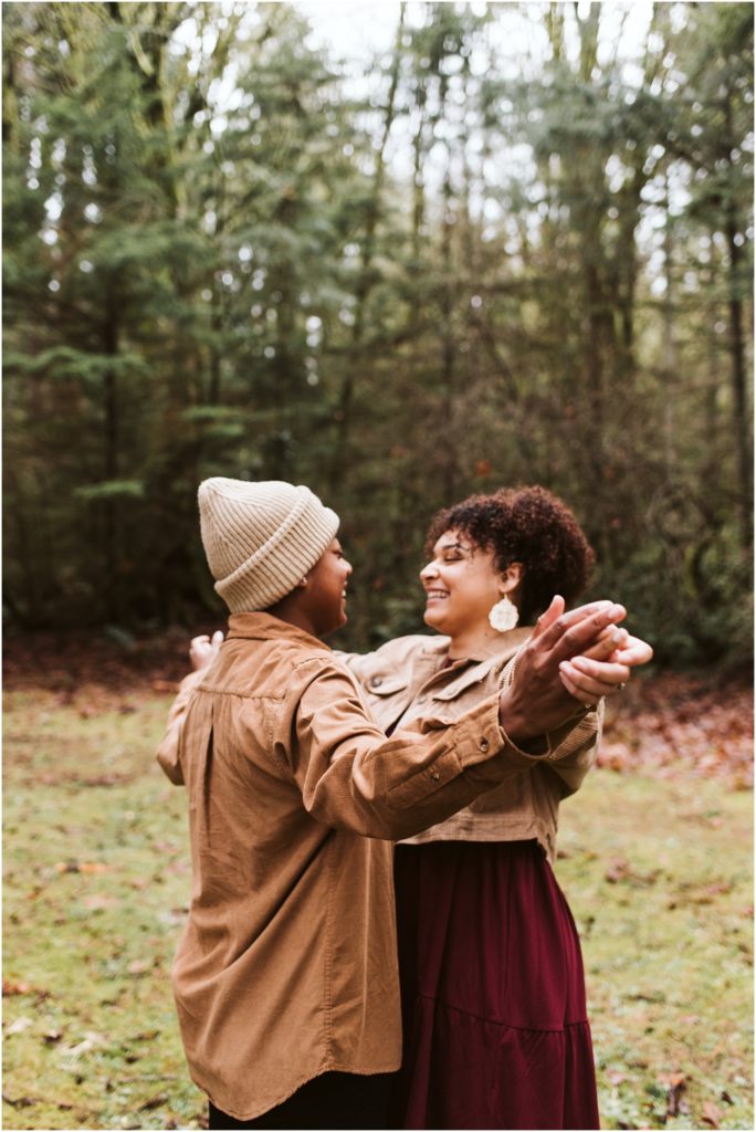 An LGBTQ+ couple holding hands and giggling during their Point Defiance engagement session