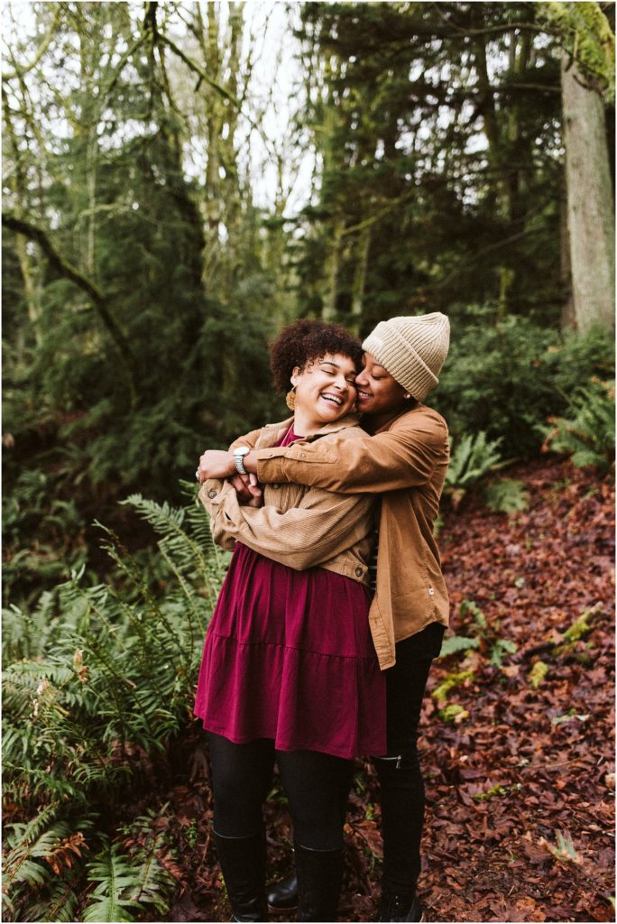 An LGBTQ+ couple embracing, one behind the other, during their Point Defiance engagement session