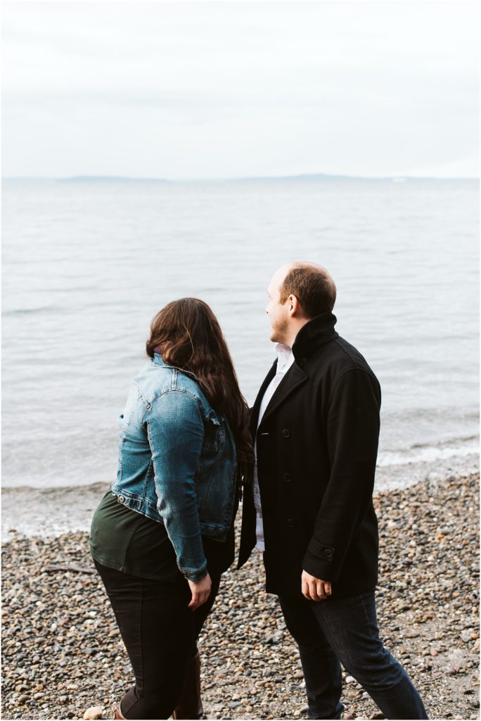 An engaged couple staring out across Puget Sound during their Seahurst Park engagement session