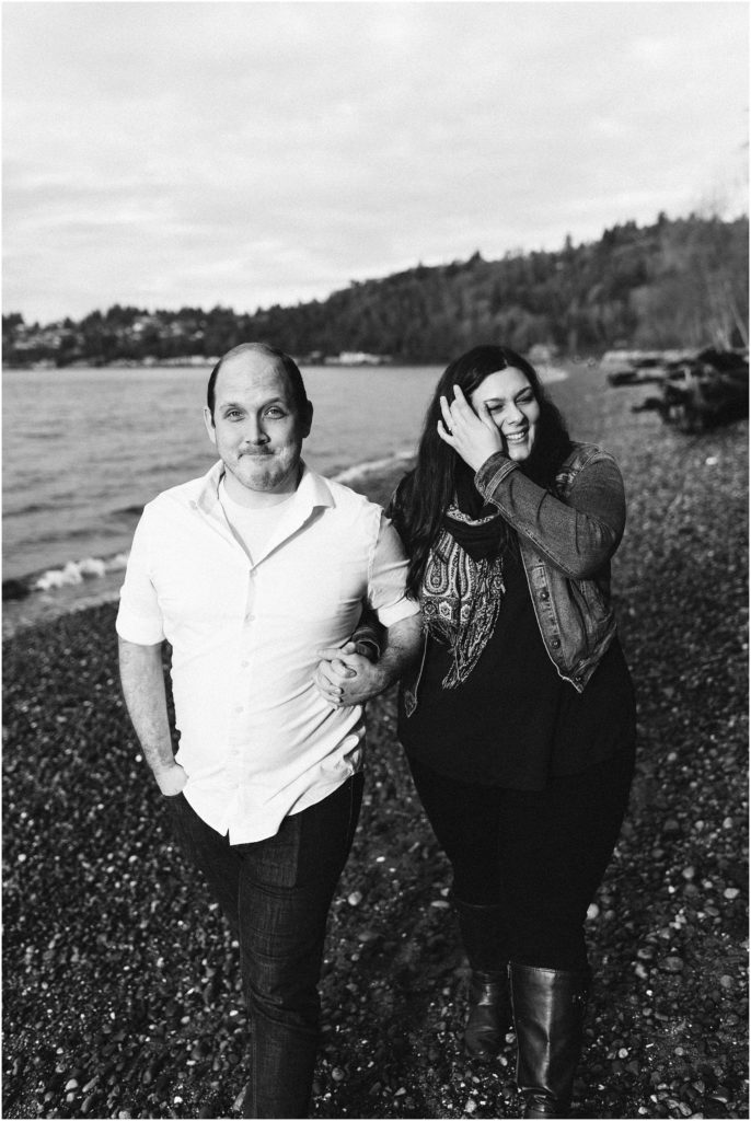 An engaged couple walking down the beach on Puget Sound, arm in arm, during their Seahurst Park engagement session