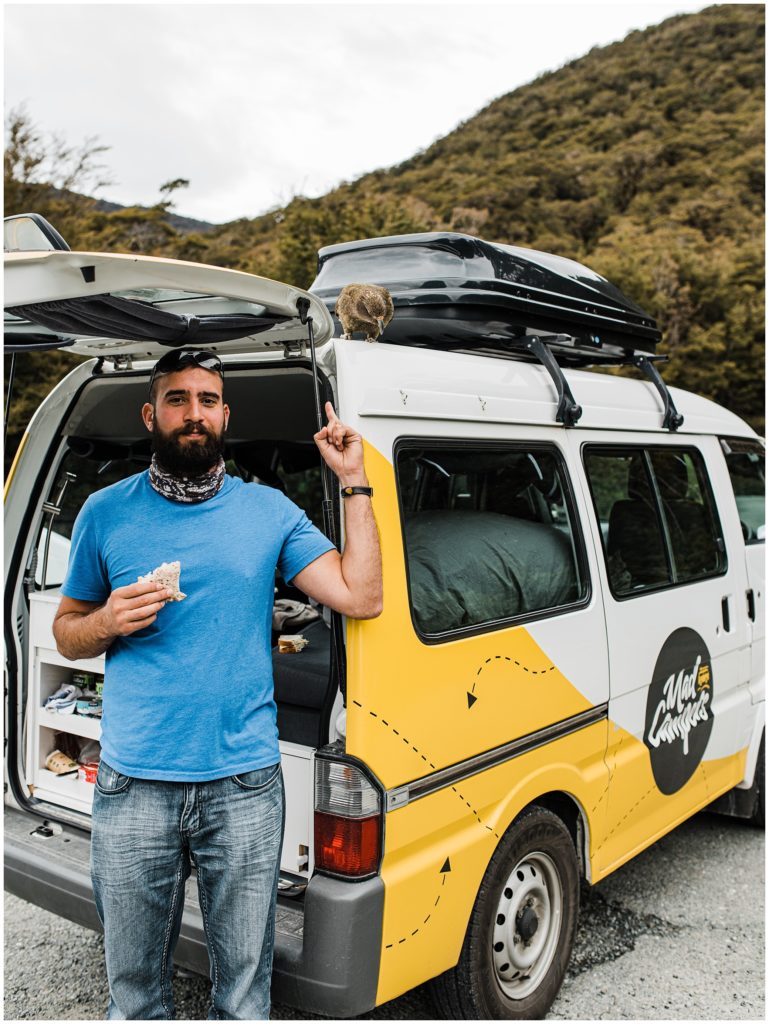 How to travel New Zealand in a campervan, making sandwiches with a kea on the van